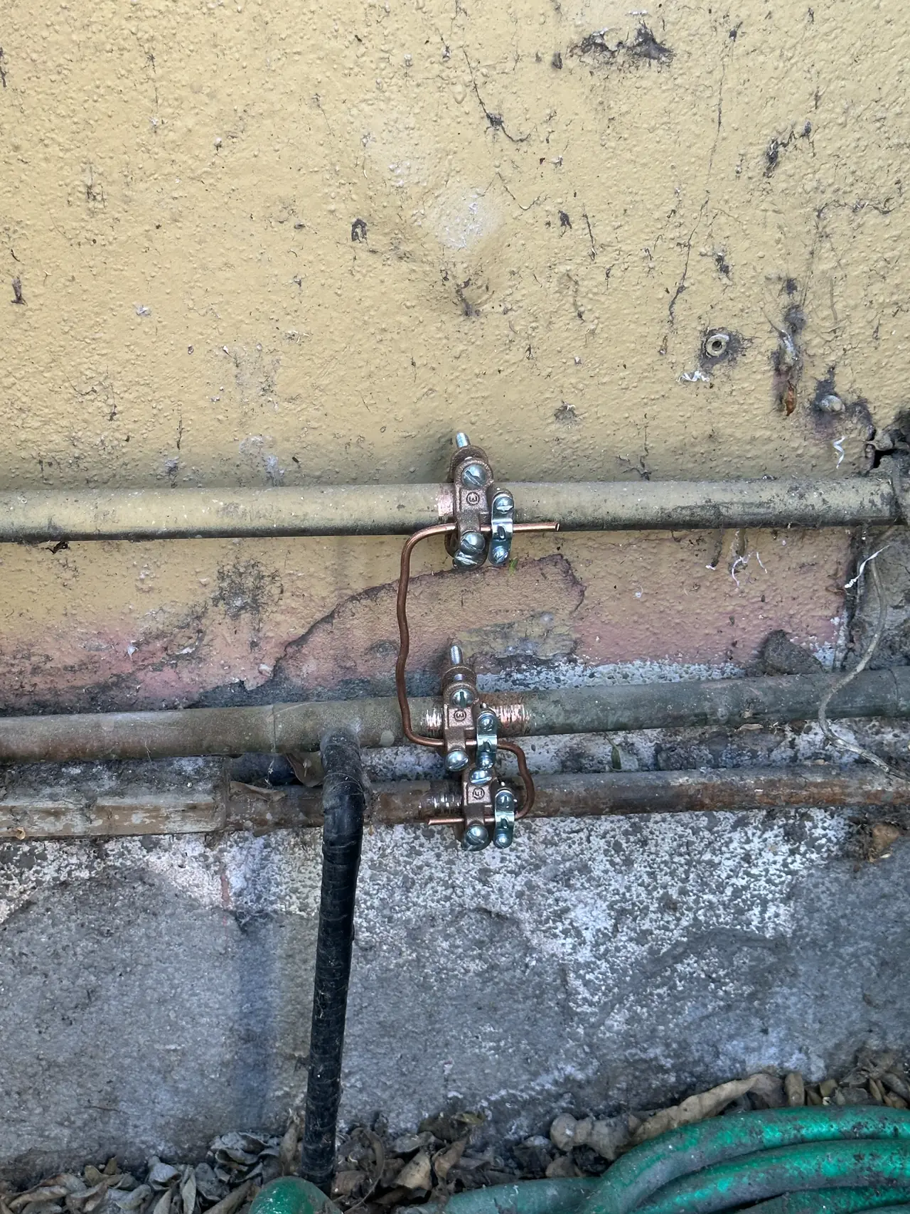 Conduit and grounding running along the base of a stucco wall beside the equipment, Long Beach