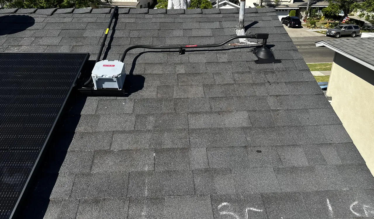A conduit run crossing the ridge of a shingle roof between two module groups, Long Beach