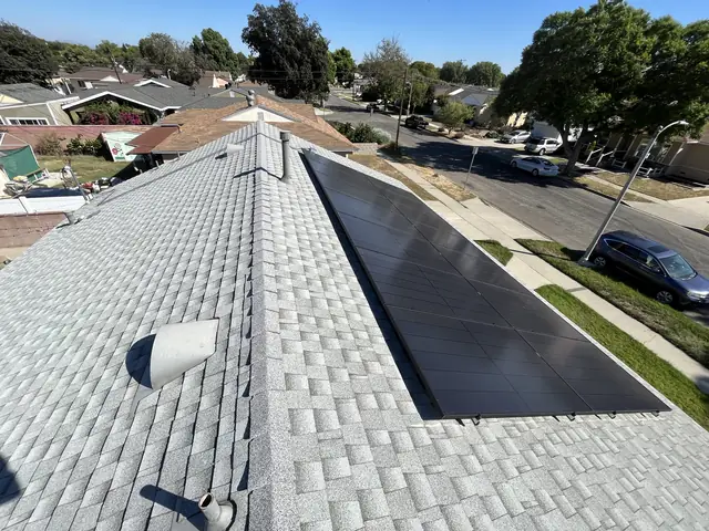 A solar array running along the slope of a shingle roof above a quiet street, Long Beach