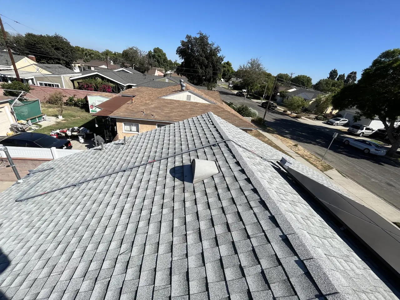 Solar modules along a shingle roof with the street and neighboring rooftops beyond, Long Beach