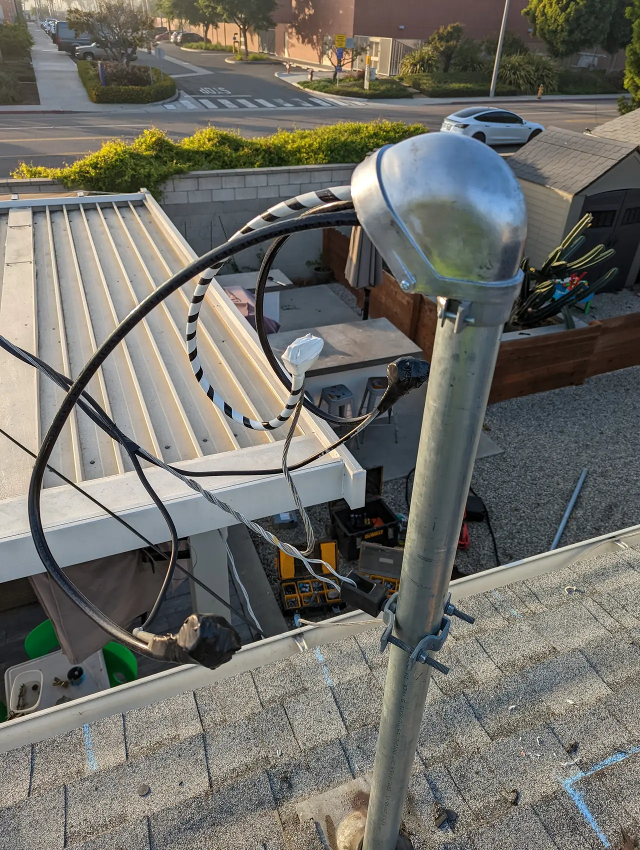 A new galvanized service mast with its weather head above a shingle roof, with the utility conductors landed on it, Long Beach
