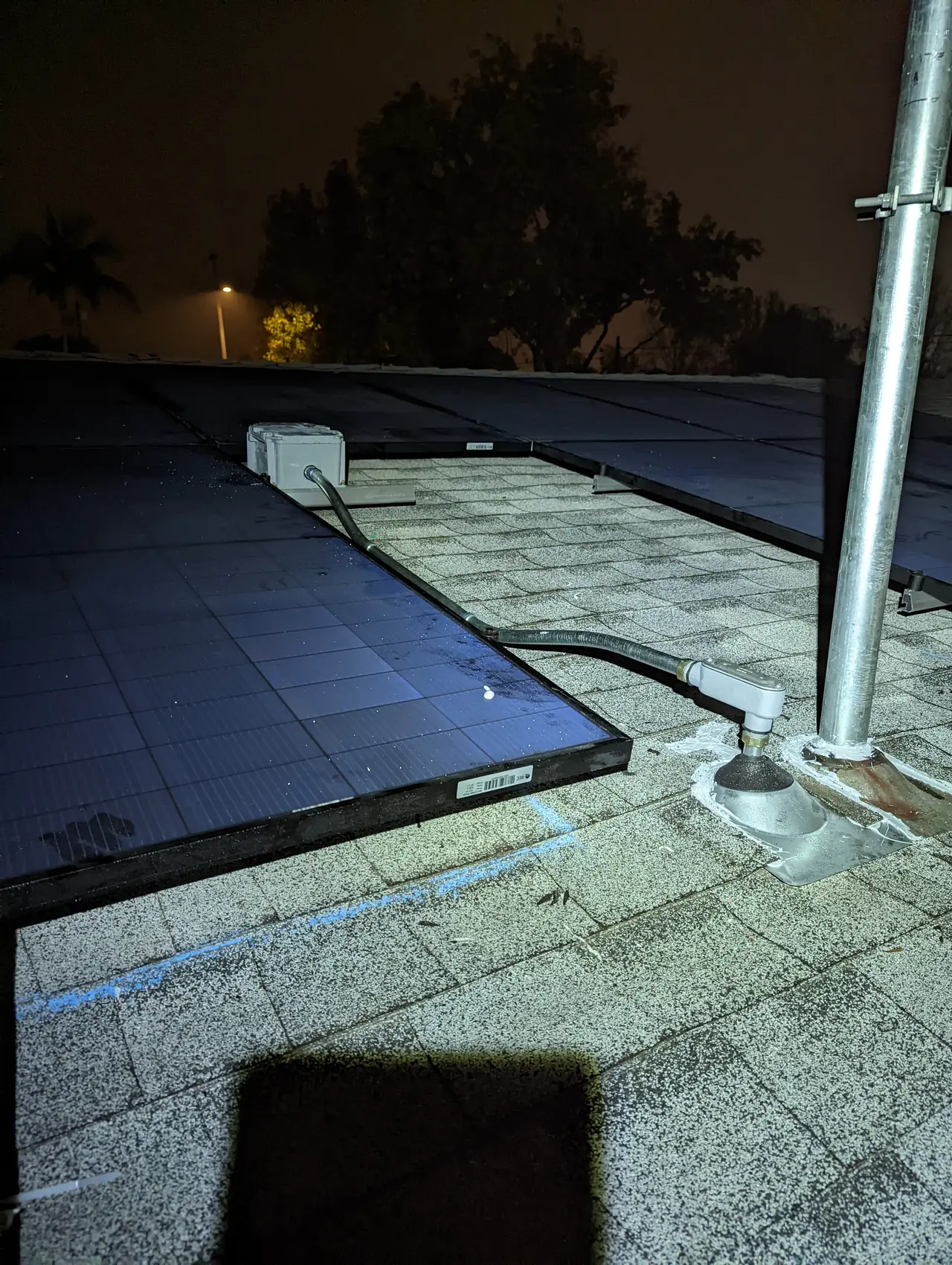 A solar array on a flat section of roof beside the new service mast at dusk, Long Beach