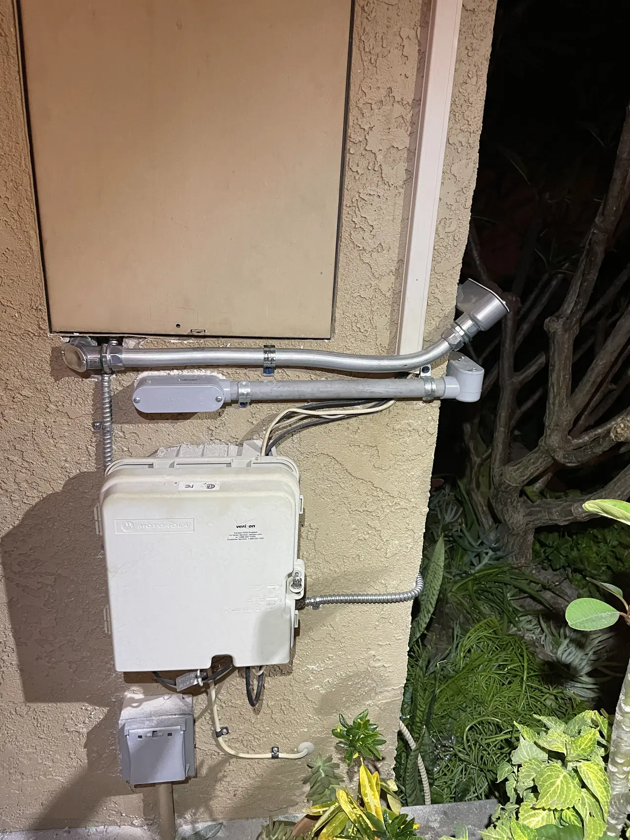 Conduit running down a stucco wall to the service equipment below the roof line, Long Beach