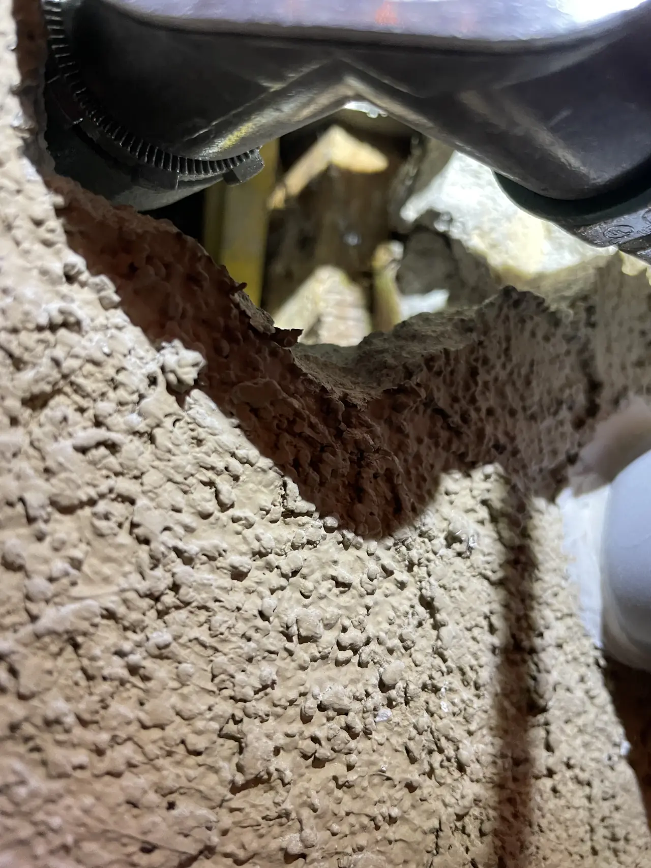 An opening cut in stucco around a conduit penetration, broken back to the framing behind it, Long Beach