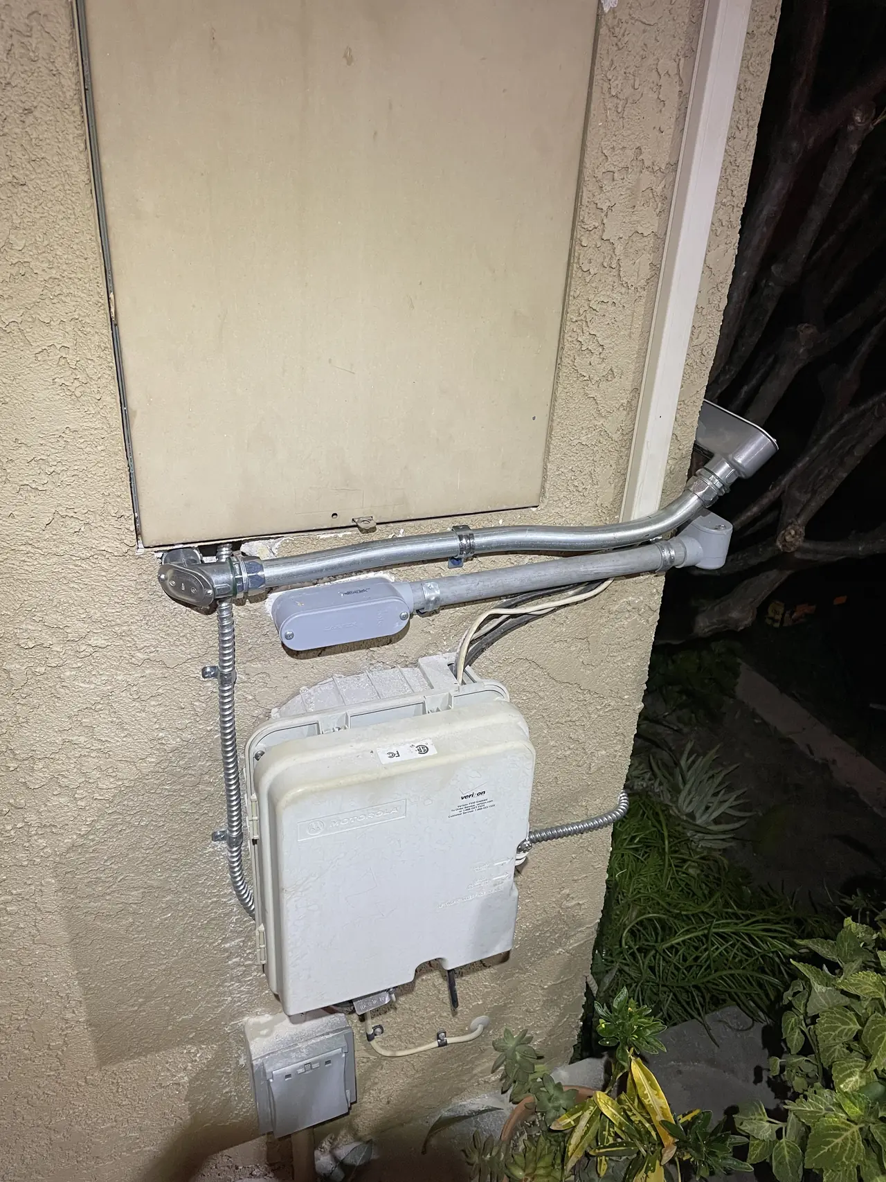 Solar service equipment mounted on a stucco wall with bare galvanized conduit running to it, Long Beach