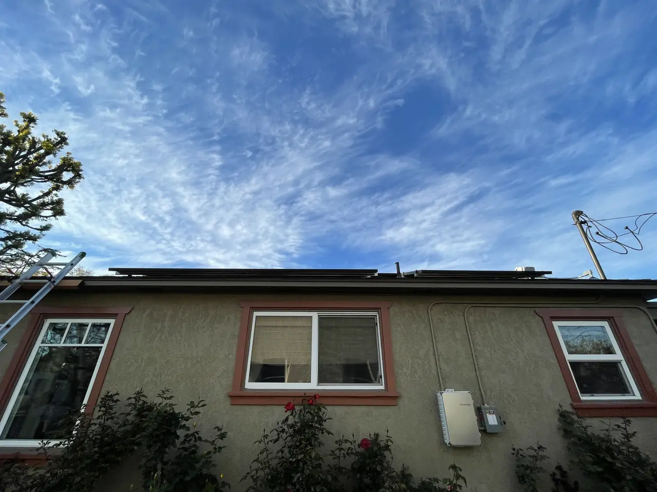 A module lead clipped to an aluminum rail above the shingle with the flashed mount below, Long Beach