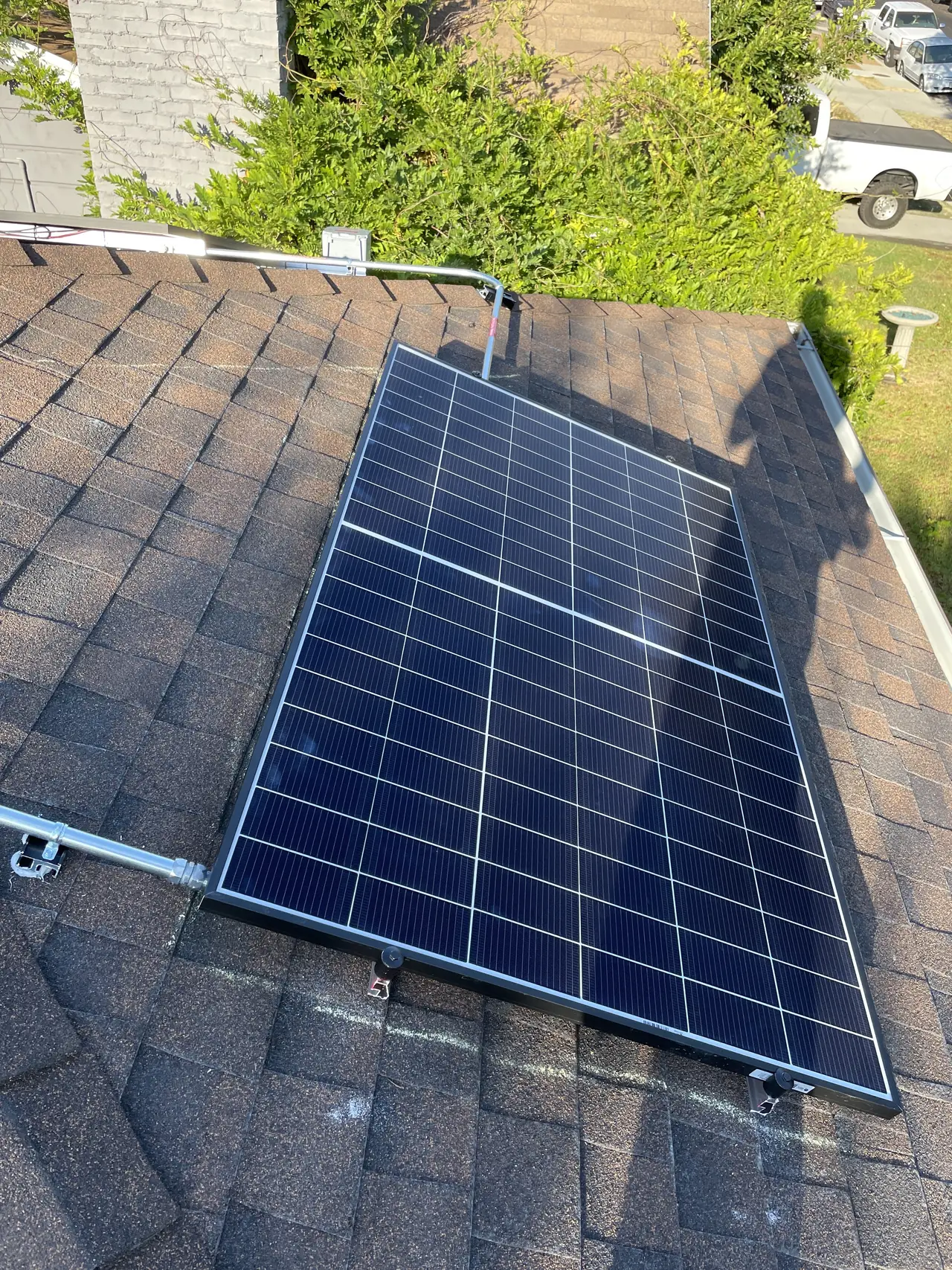 A solar module and its mounting rail seen close up on a shingle roof, El Sereno, Los Angeles