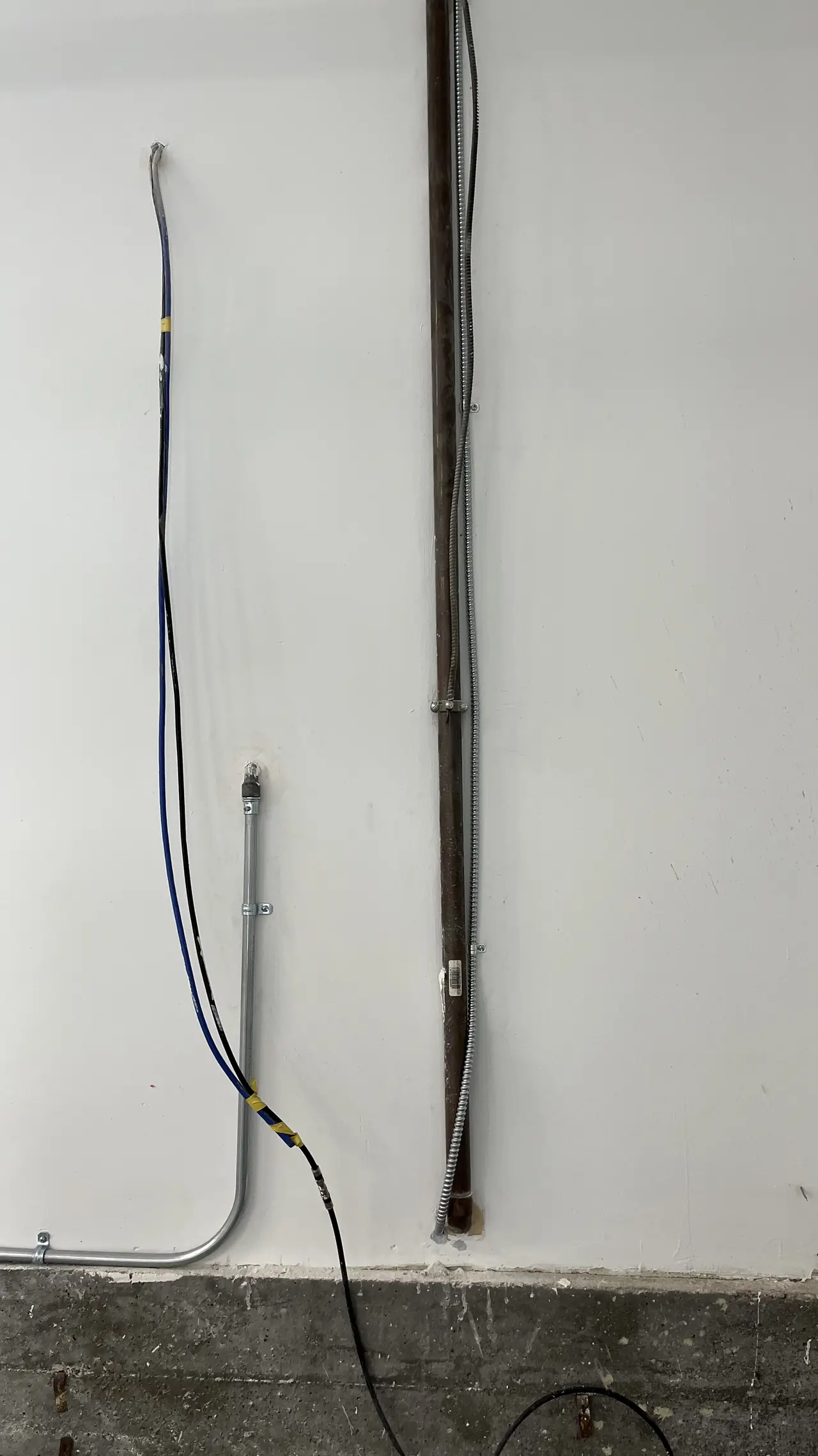 A bonding conductor and metal conduit running down an exterior stucco wall to grade, Brentwood, Los Angeles