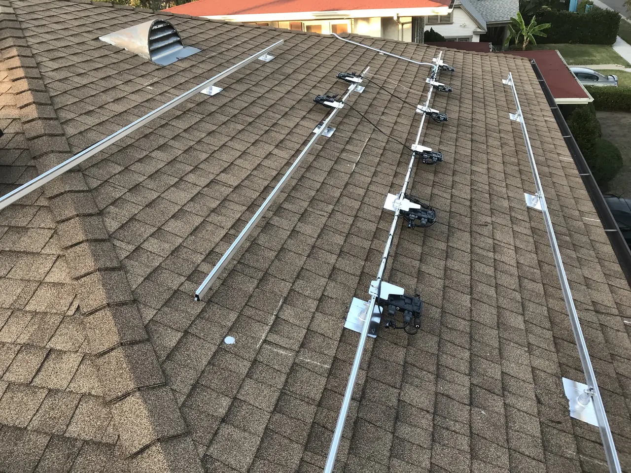 Mounting rails and micro-inverters laid out across a composition shingle roof before modules are set, West Adams, Los Angeles