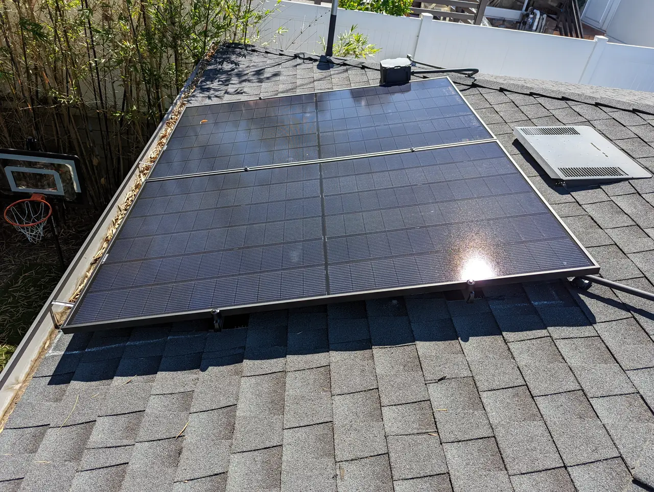 Solar modules laid across a shingle roof above a back garden, Cypress Park, Los Angeles