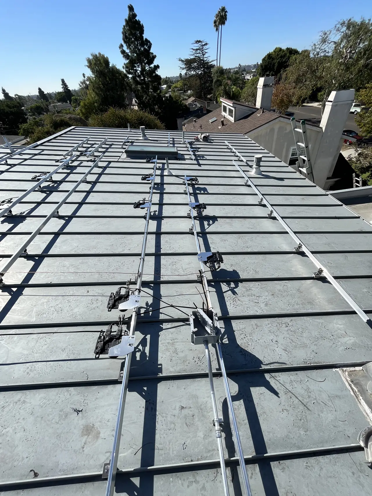 Mounting rails and micro-inverters set out across a low-slope roof before the modules go on, Mar Vista, Los Angeles