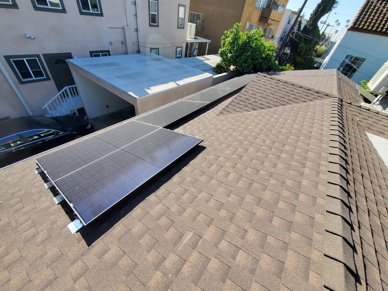 Solar modules on a hipped composition shingle roof with neighboring buildings behind, Los Feliz, Los Angeles