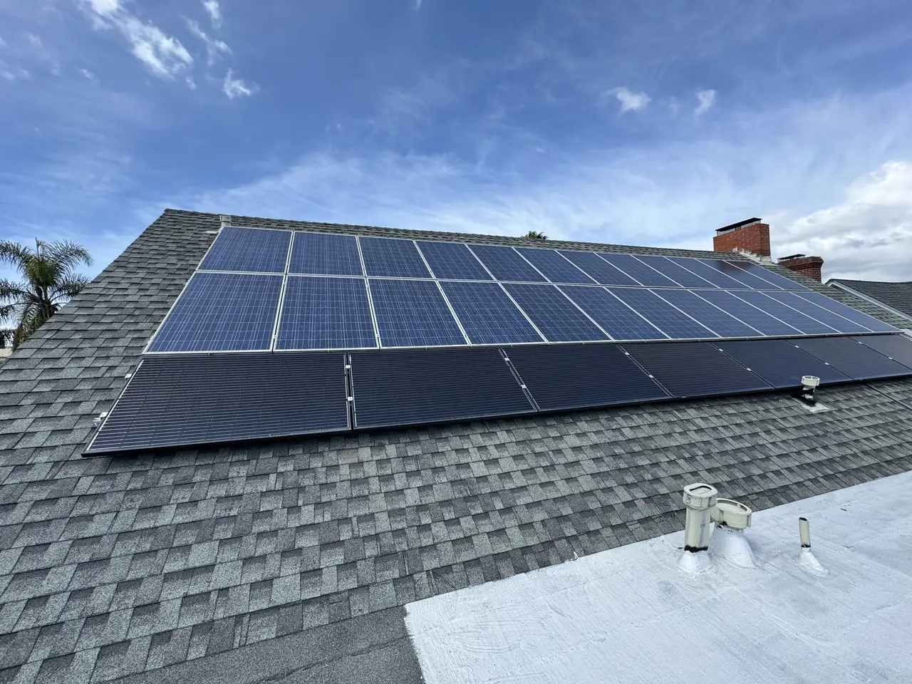 An existing rooftop solar array on a shingle roof under a clear sky, Windsor Square, Los Angeles
