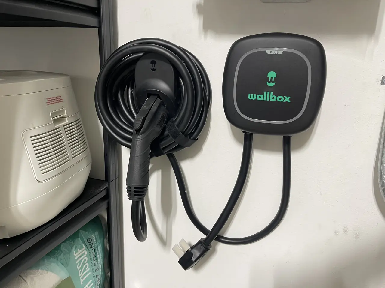 A level 2 electric vehicle charger mounted on an exterior wall with its cable coiled, Atwater Village, Los Angeles