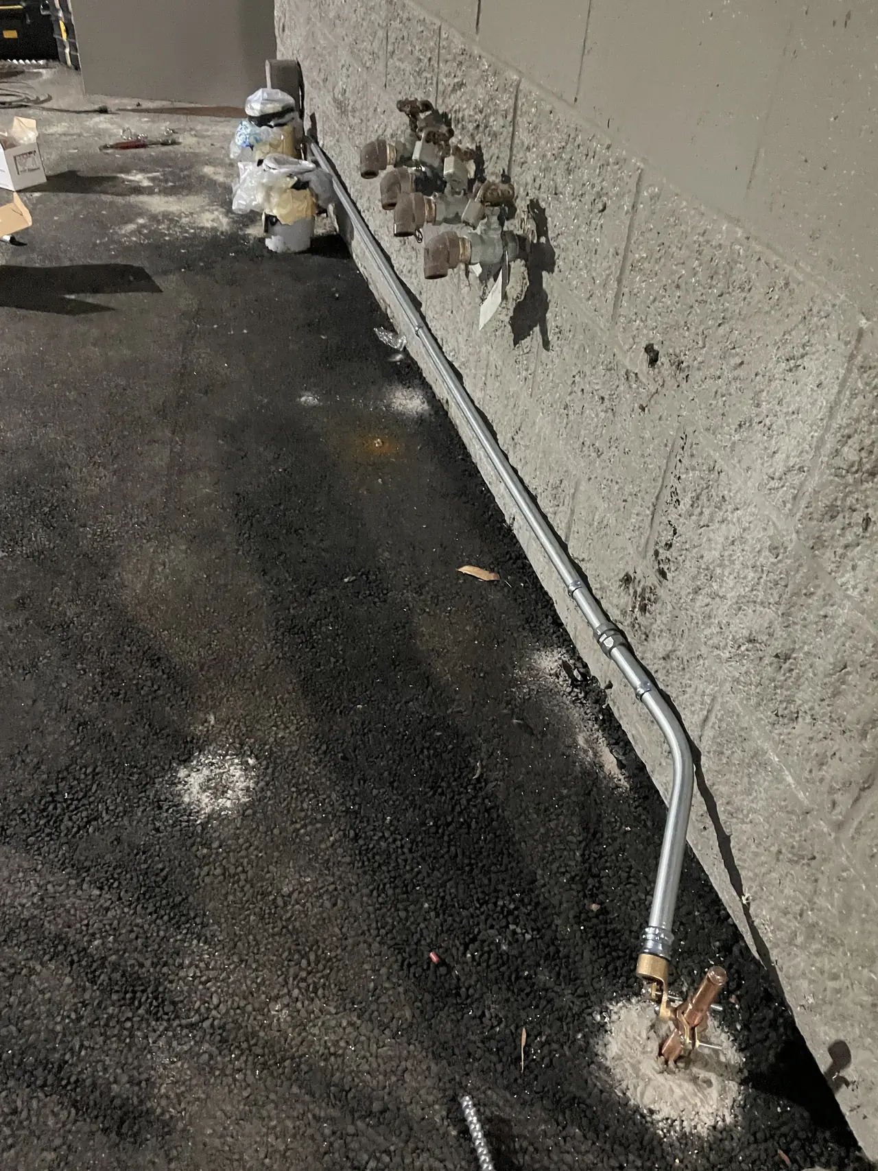 Conduit and a grounding conductor run along the base of an exterior wall, Palms, Los Angeles