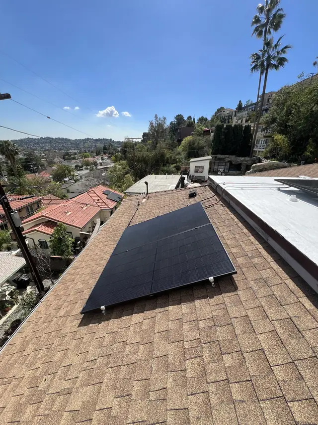 Solar modules on a composition shingle roof with clouds and the hillside beyond, Glassell Park, Los Angeles