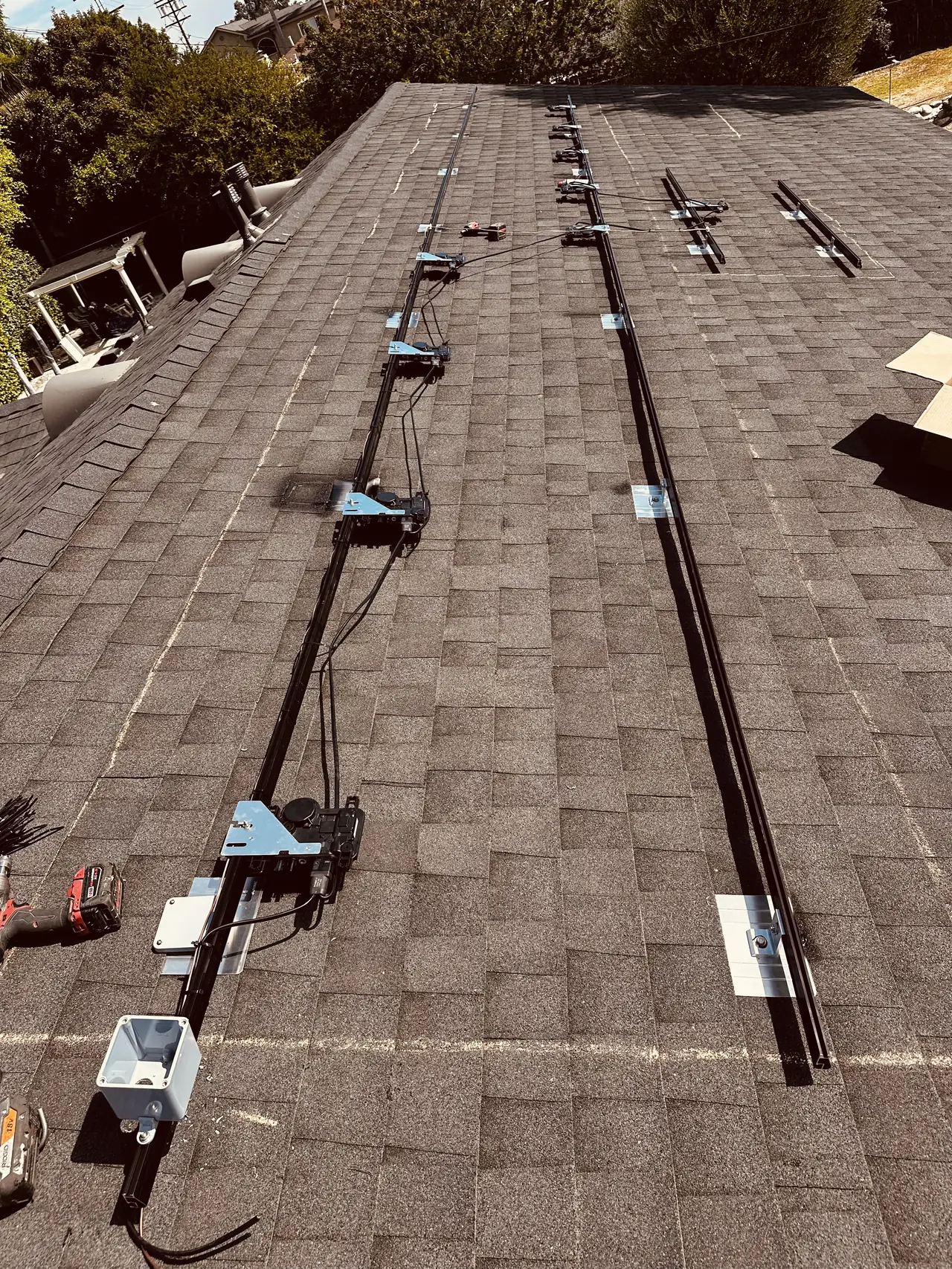Mounting rails laid in rows across a shingle roof before the modules, South Los Angeles