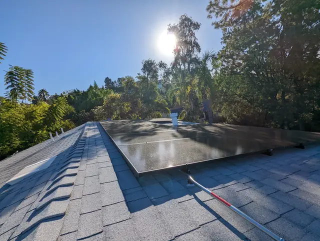 Solar modules on a shingle roof with trees and low sun, Hollywood Hills, Los Angeles