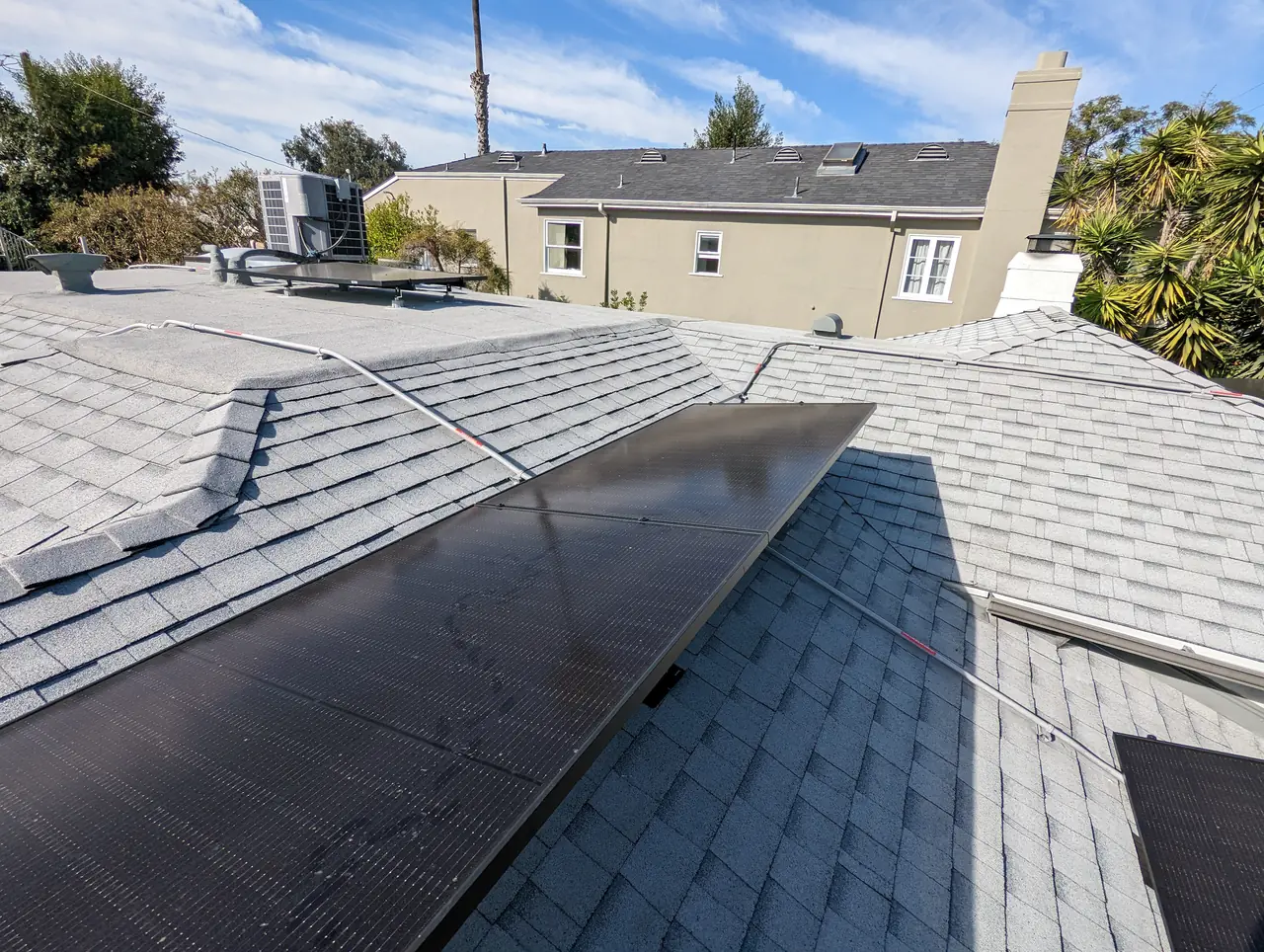 Solar modules on a composition shingle slope with neighboring rooftops beyond, Mid-City, Los Angeles