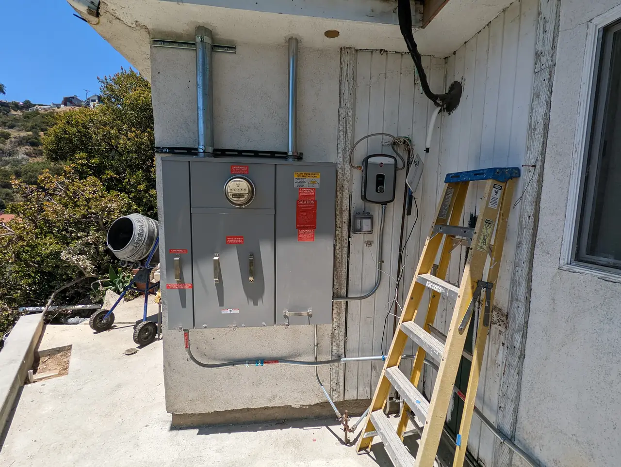 An exterior wall carrying service equipment with a ladder propped beside it during a service replacement, Hollywood Hills, Los Angeles