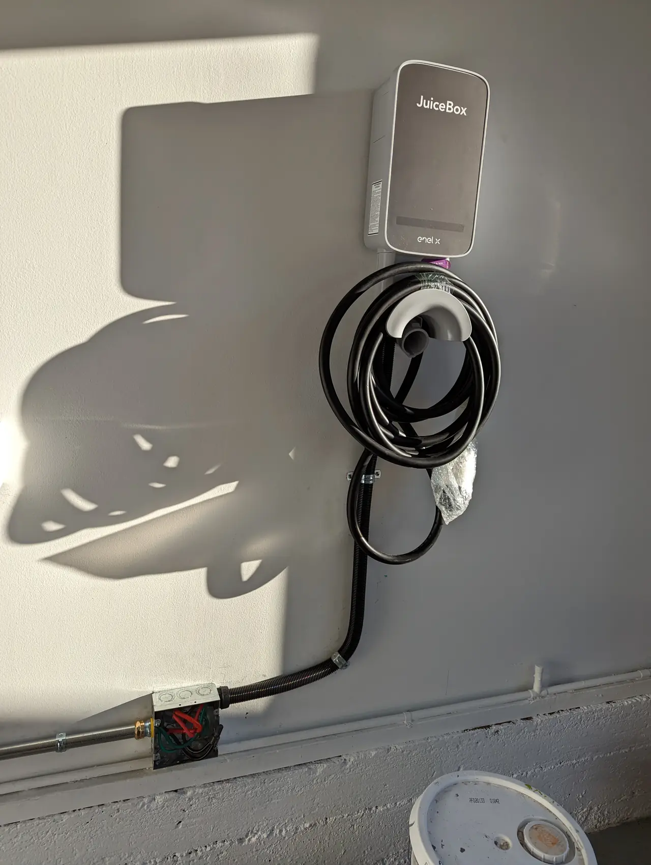 A wall-mounted vehicle charging unit with its cable coiled beneath it, Westchester, Los Angeles