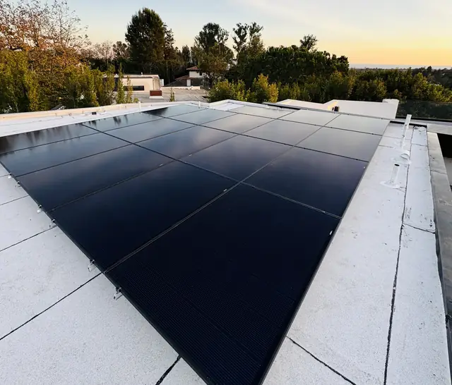 Solar modules on a low-slope roof against an evening sky, Brentwood, Los Angeles