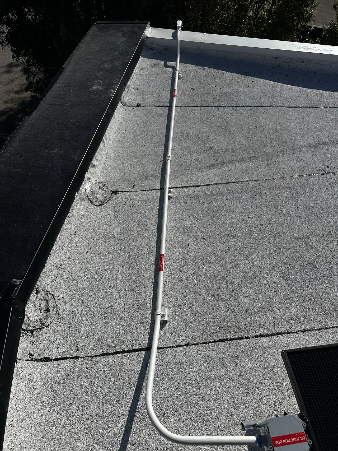 A conduit run crossing a white low-slope roof between module groups, Brentwood, Los Angeles