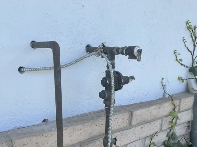 Conduit risers and a service head against a block wall beside a hillside house, Hollywood Hills, Los Angeles