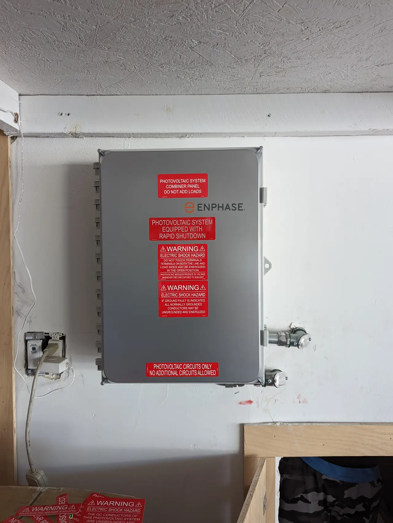 A combiner enclosure mounted on an exterior wall with its rapid-shutdown and warning labels, Hollywood Hills, Los Angeles