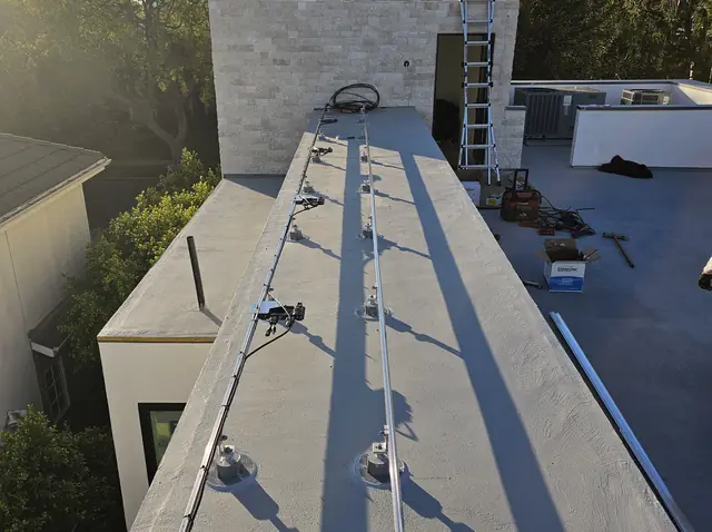 Mounting rails on a white low-slope roof at first light with the neighborhood beyond, West Los Angeles