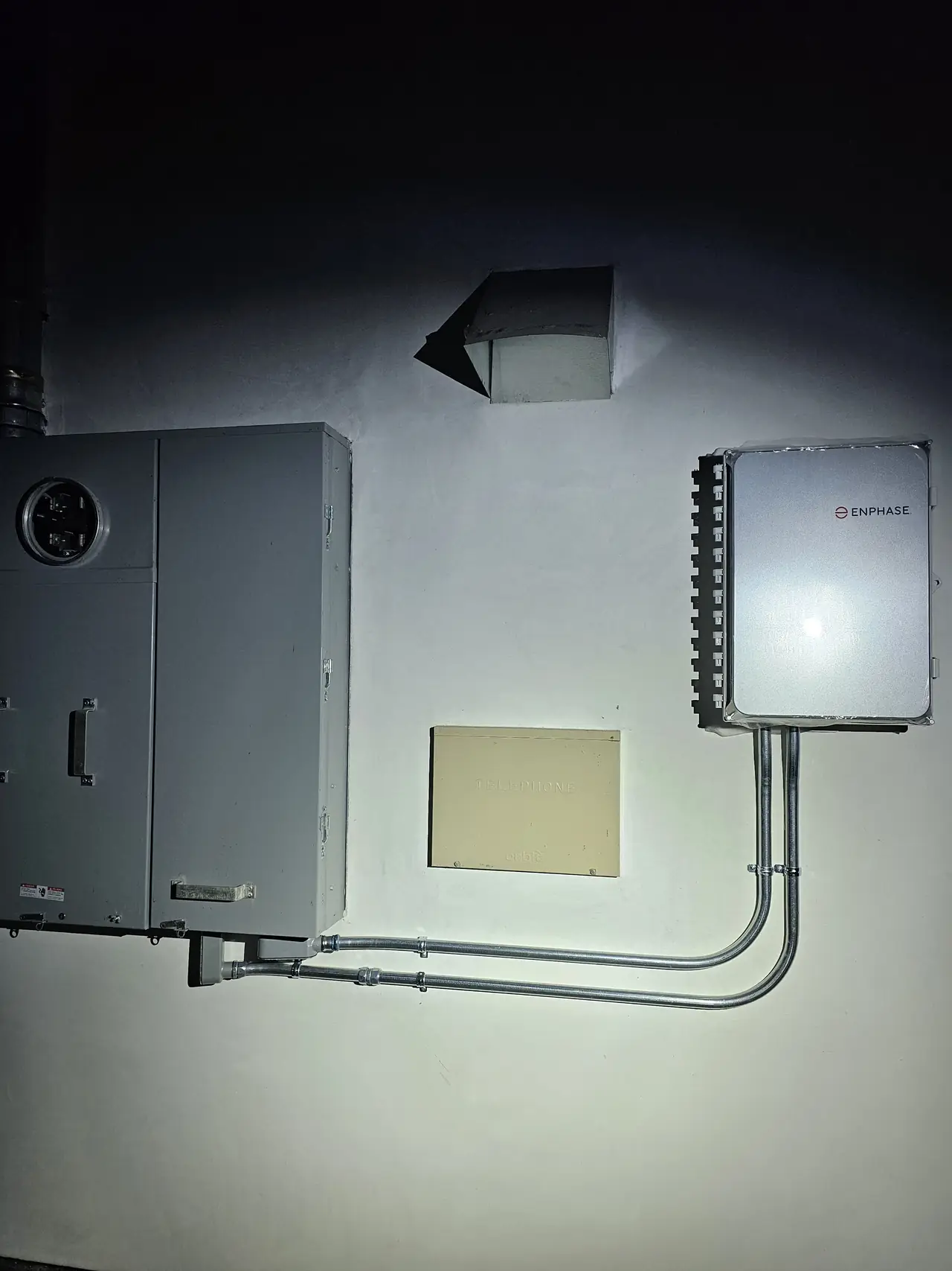 A meter panel and a closed gateway enclosure side by side on an exterior wall, photographed after dark, West Los Angeles