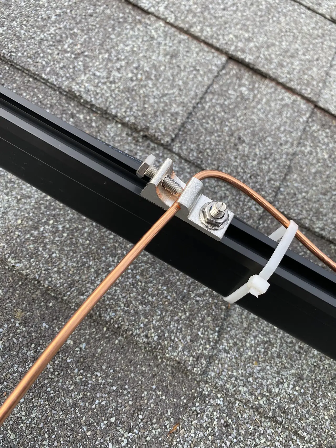 A grounding conductor clamped to a mounting rail on a composition shingle roof, Hollywood Hills, Los Angeles