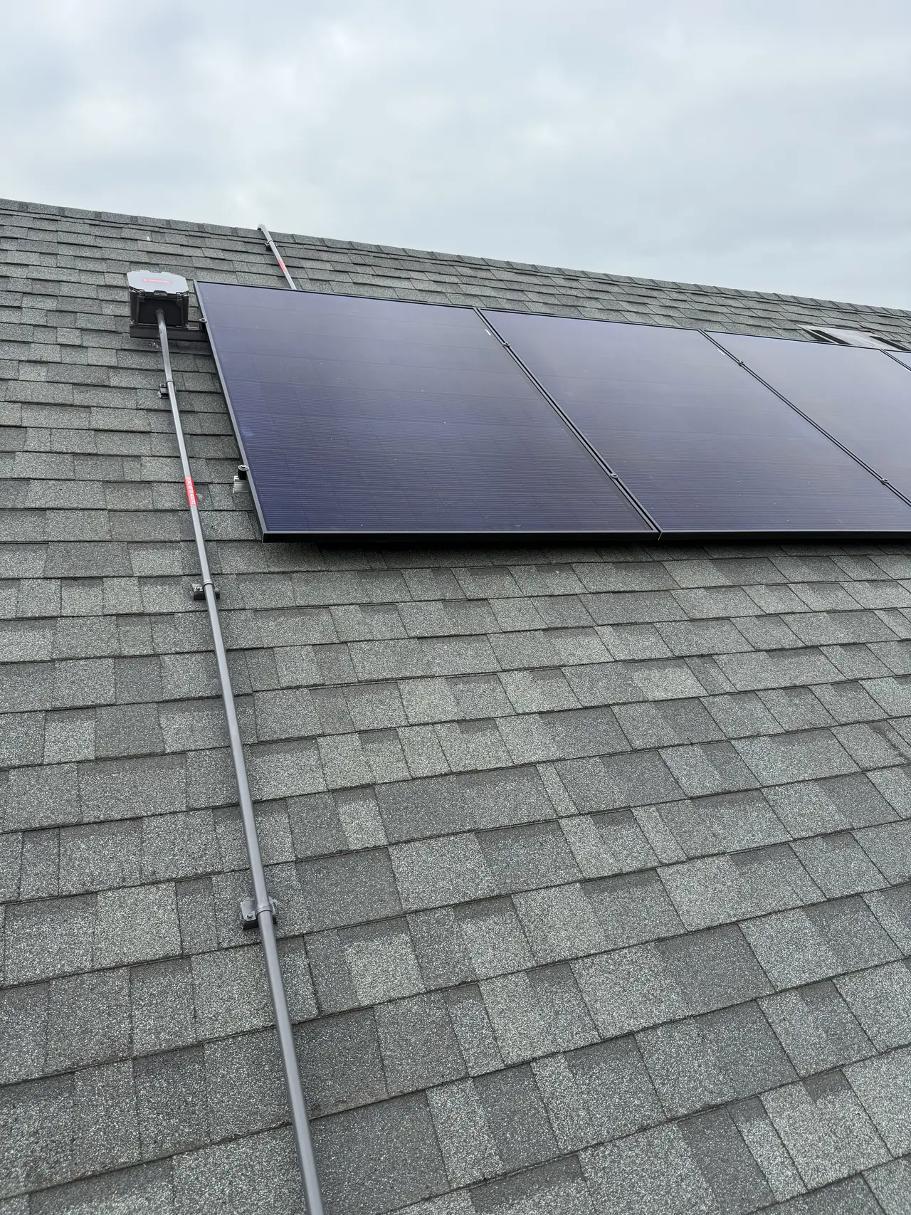 Solar modules near the ridge of a composition shingle roof under overcast sky, Mid-City, Los Angeles