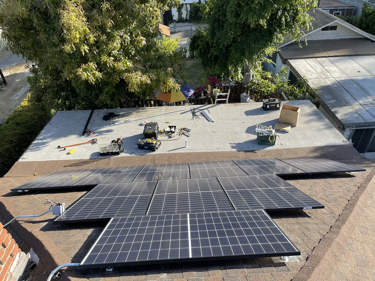 A solar array laid across the junction of a pitched composition shingle roof and an adjoining low-slope section, Echo Park, Los Angeles