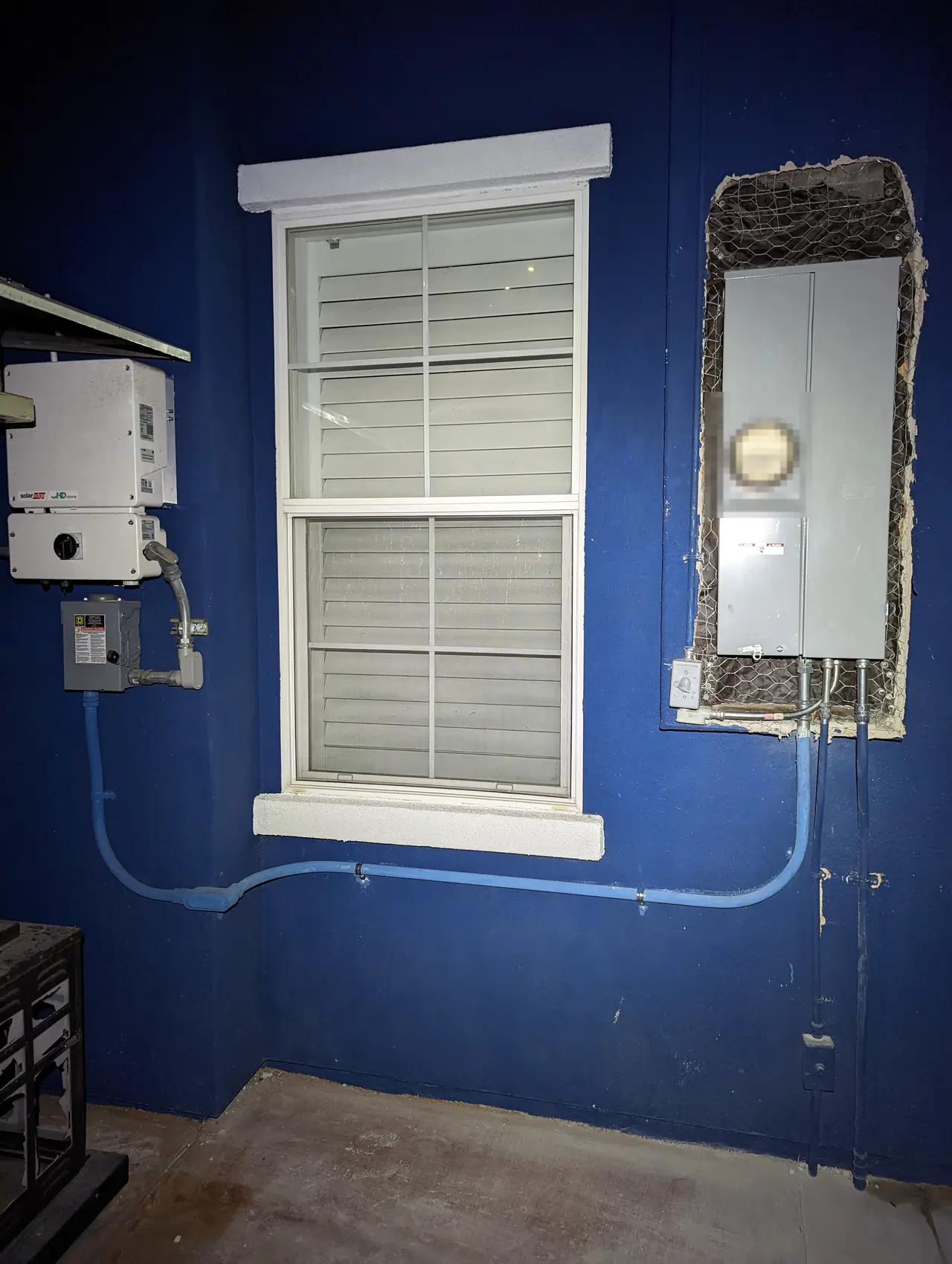 A new meter and service panel set into an opening in a blue stucco wall, with a SolarEdge inverter to the left, Mission Hills