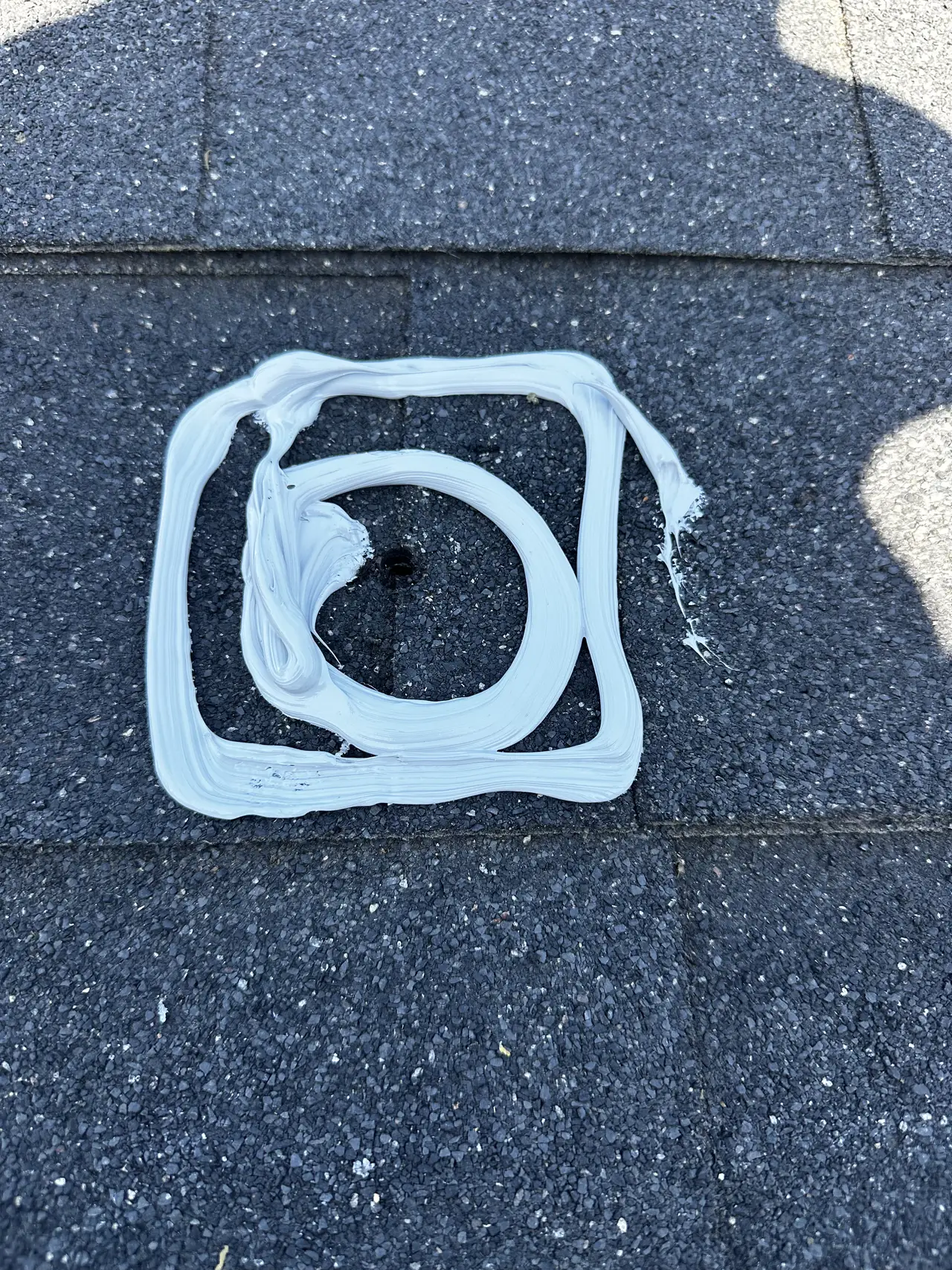 A double ring of sealant around a drilled mount hole on a dark shingle roof, Mission Hills