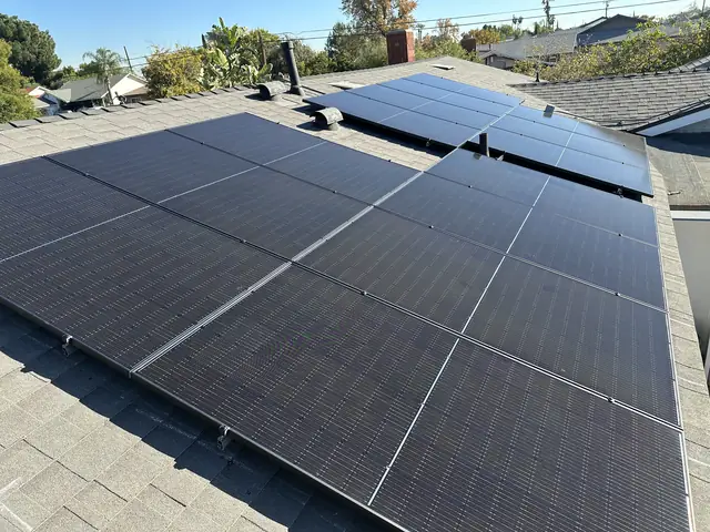 Two fields of black solar modules on a gray shingle roof under a clear sky, Mission Hills
