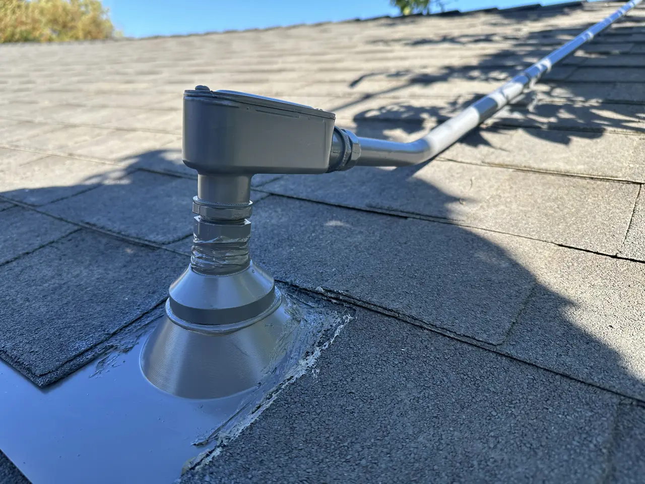 Conduit entering a shingle roof through a flashed fitting, Mission Hills