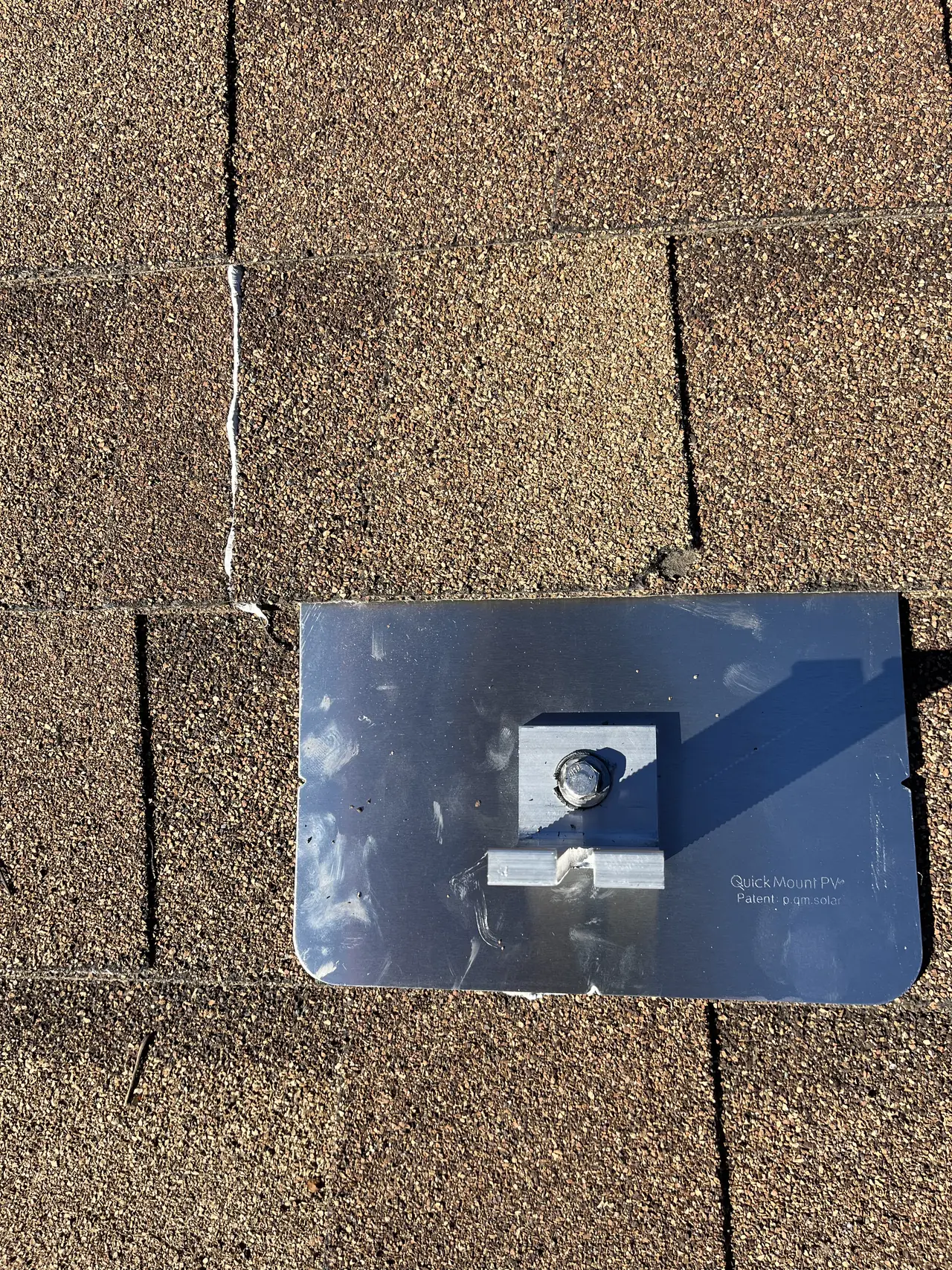 A metal flashing with an L-foot bolted down, set under a brown shingle course, Mission Hills