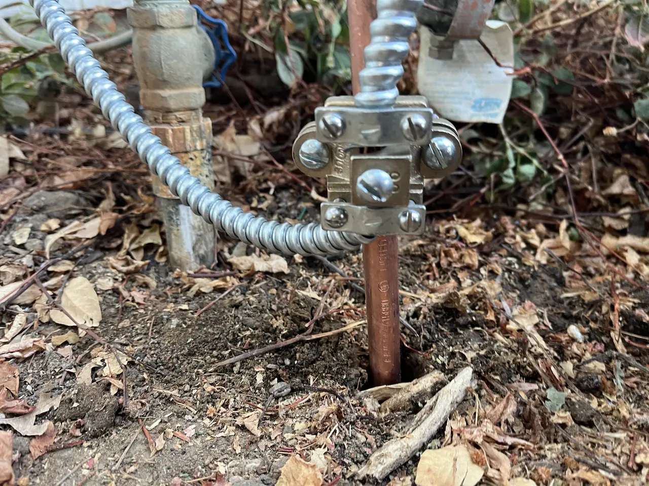 A grounding electrode conductor clamped to a copper ground rod driven into the soil beside the service pipes, North Hills, Los Angeles