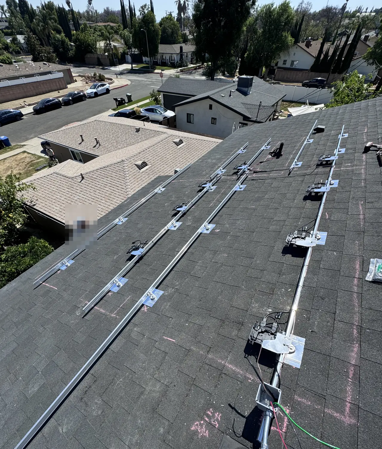 Aluminum rails and microinverters attached along a shingle roof before the modules are set, North Hills, Los Angeles