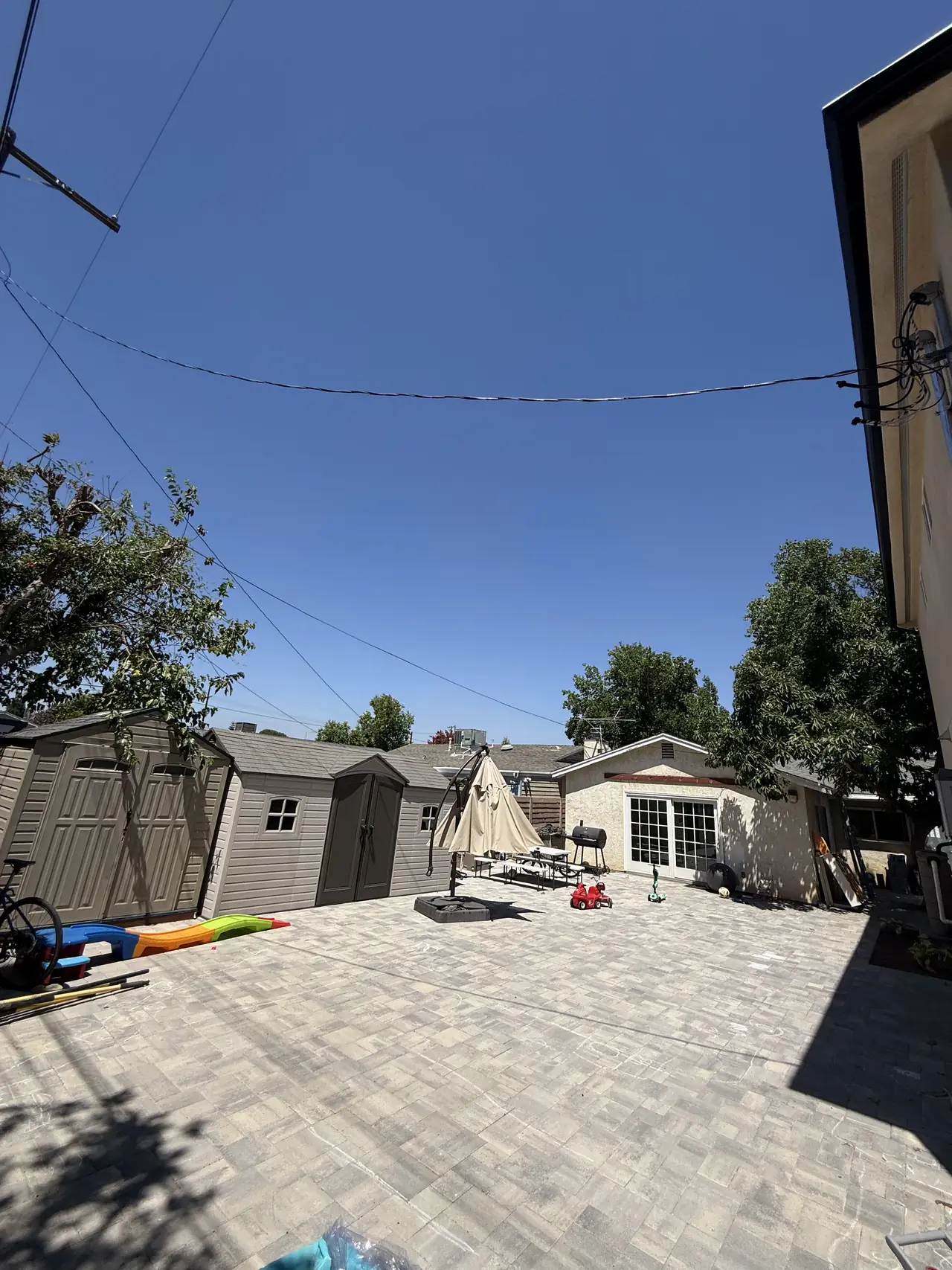 A paved yard beside a newly built dwelling under a clear sky, North Hills, Los Angeles