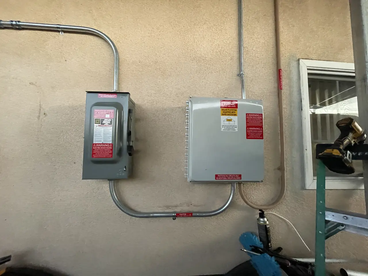Two service enclosures side by side on a stucco wall, joined by conduit, at dusk, North Hills, Los Angeles