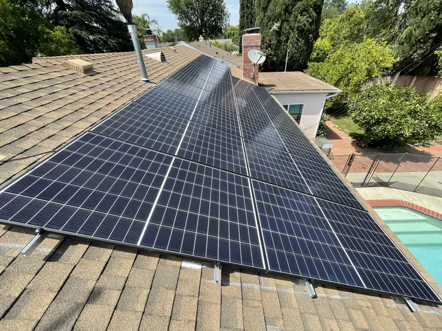 A completed solar array running along a shingle roof plane with a swimming pool in the yard below, North Hills, Los Angeles