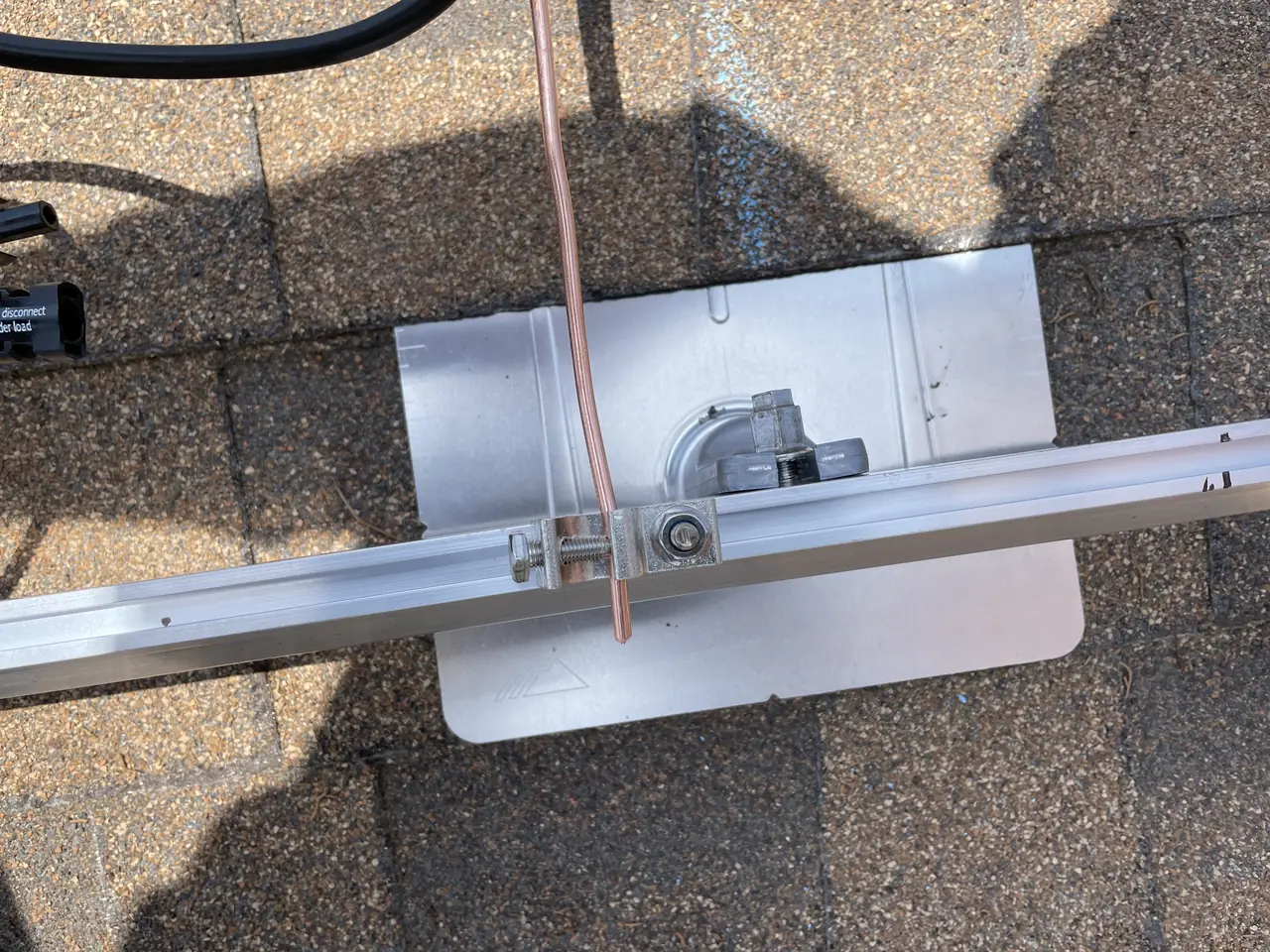 A mounting bracket and flashing set into a shingle roof with an aluminum rail above it, North Hills, Los Angeles