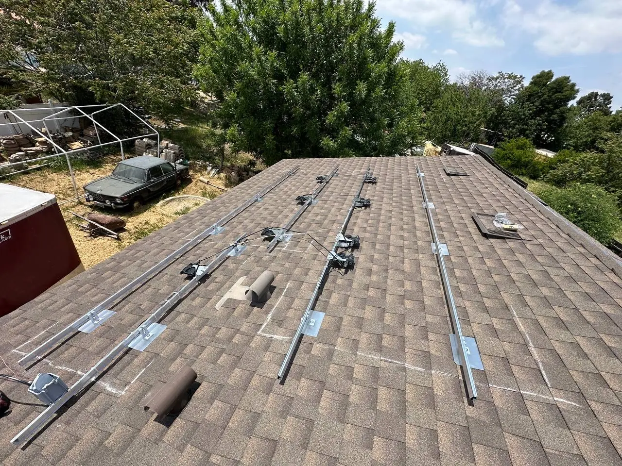 Chalk marks and the first aluminum rails set out across a shingle roof before the modules go on, North Hills, Los Angeles