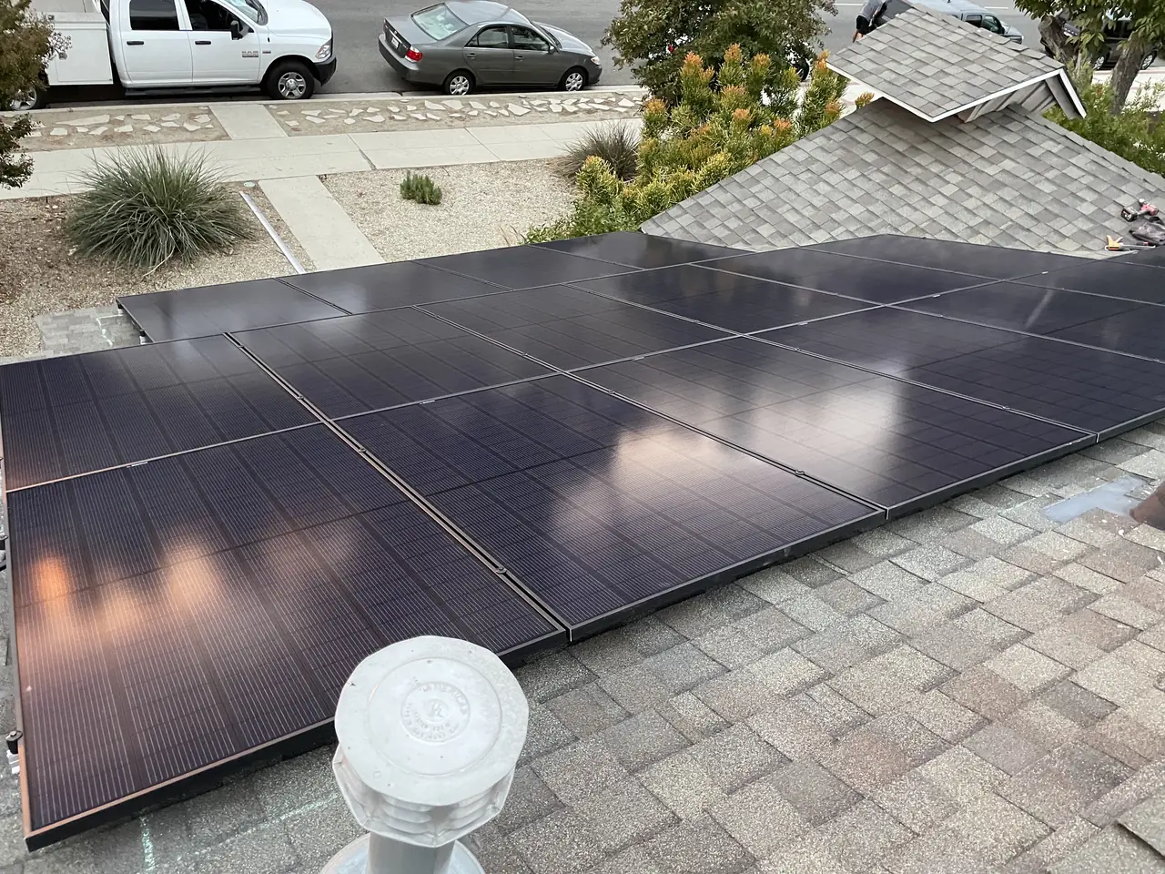 A group of solar modules on the street-facing plane of a shingle roof with a parked vehicle beyond, North Hills, Los Angeles