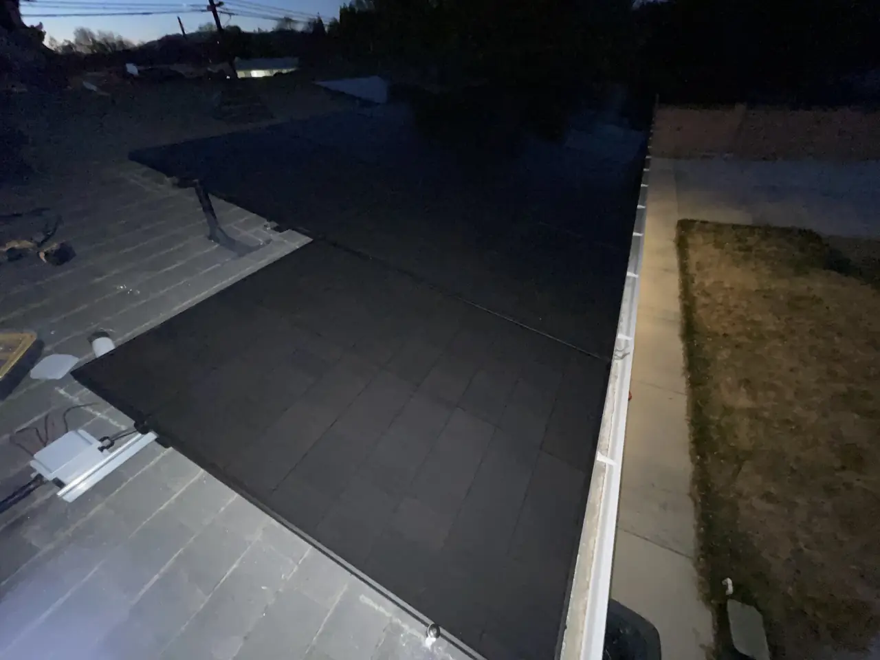 The edge of a solar array along a shingle roof slope after sunset, North Hills, Los Angeles