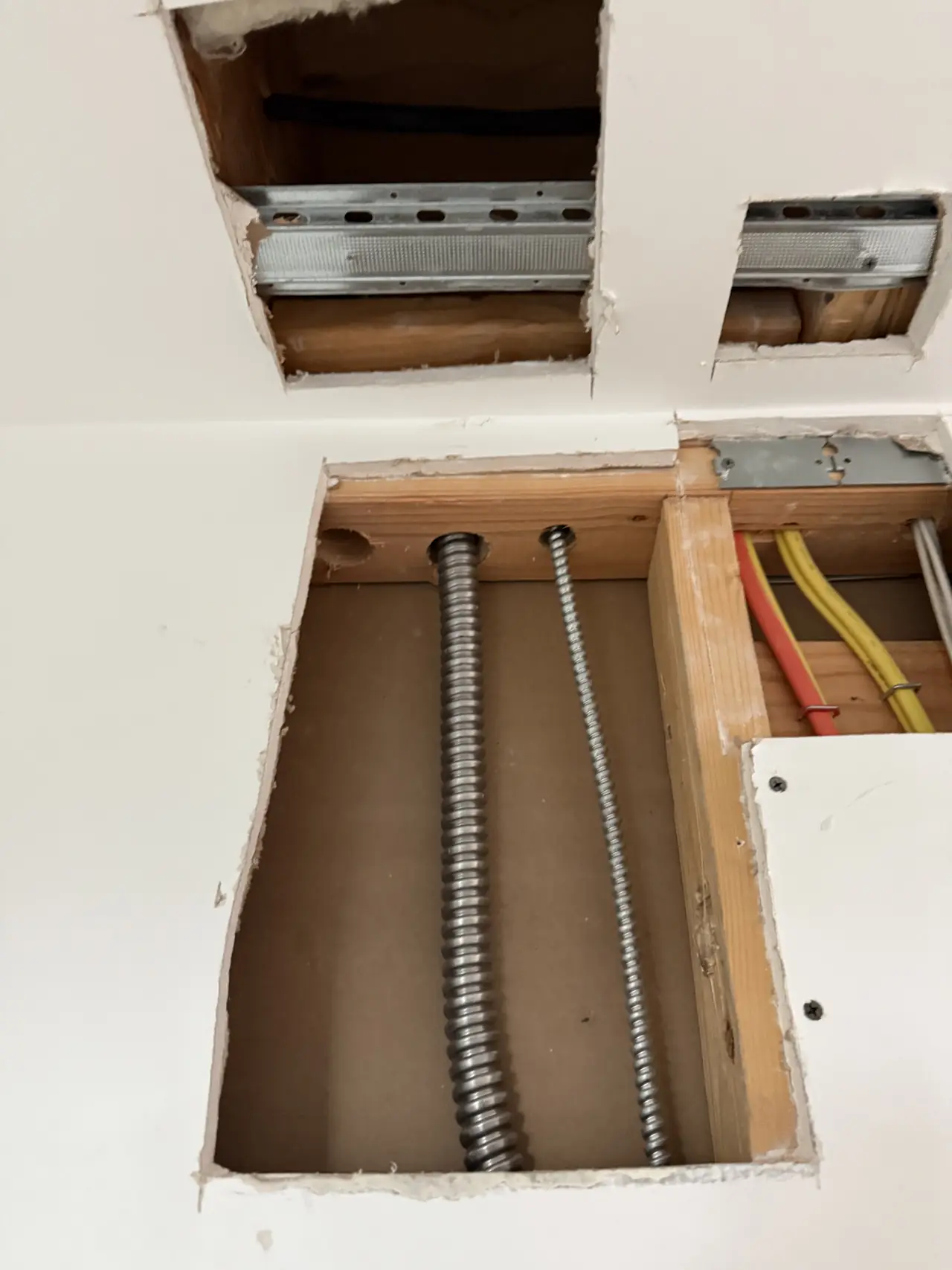 Ceiling opened to show flexible conduit running through the framing, North Hollywood