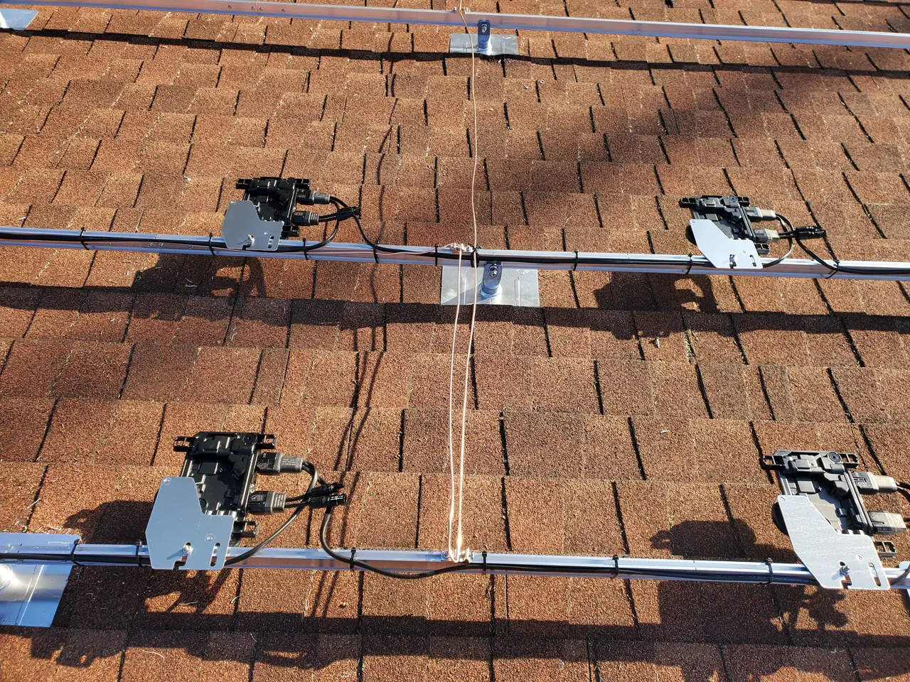 Microinverters mounted along a rail with a chalk line running across the shingle, North Hollywood